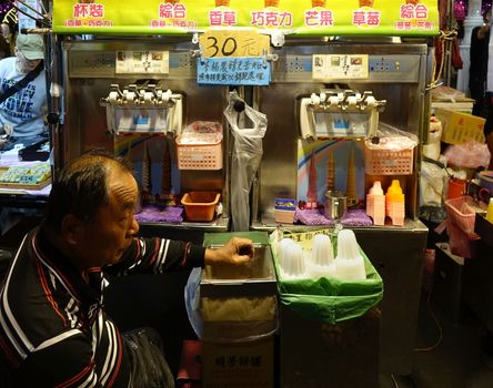 KAOHSIUNG, TAIWAN -- FEBRUARY 9, 2019: An elderly man waits for customers to buy ice cream at an outdoor food market.
