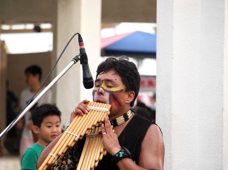 A musician from South America plays on a wooden pan flute
