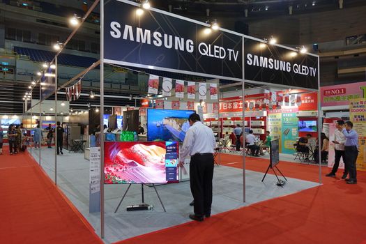 KAOHSIUNG, TAIWAN -- APRIL 5, 2019: Visitors at a sales and promotional fair for electric household appliances look at flat screen TVs.
