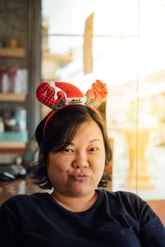 Asian woman 40s white skin have a laughing smile gesture in a coffee shop cafe with santa claus headband in merry christmas and new year celebration