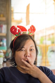 Asian woman 40s white skin have a laughing smile gesture in a coffee shop cafe with santa claus headband in merry christmas and new year celebration