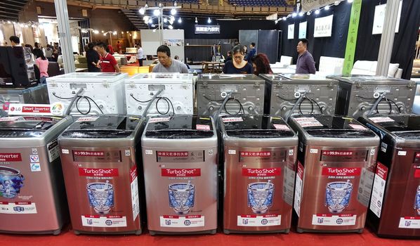 KAOHSIUNG, TAIWAN -- APRIL 5, 2019: Visitors at a sales and promotional fair for electric household appliances look at washing machines.