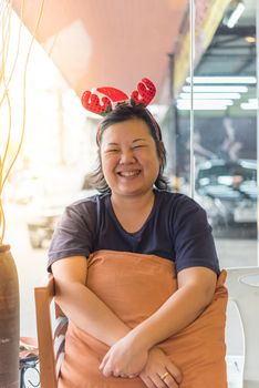 Asian woman 40s white skin have a laughing smile gesture in a coffee shop cafe with santa claus headband in merry christmas and new year celebration