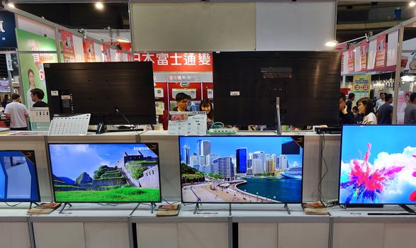 KAOHSIUNG, TAIWAN -- APRIL 5, 2019: Visitors at a sales and promotional fair for electric household appliances look at flat screen TVs.