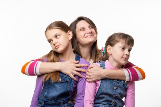 Mom happily hugs children, children turned away from mom