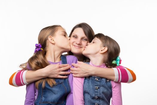 Children joyfully kiss mom, isolated on white background