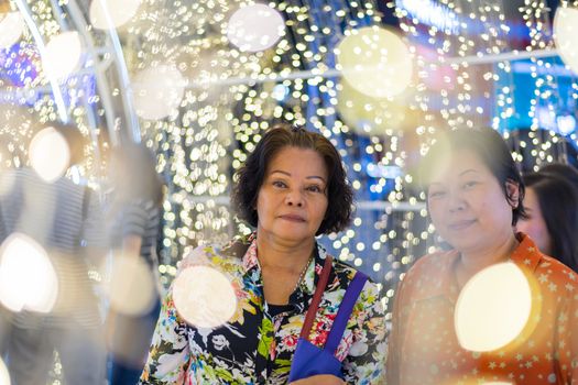 Asian women 60s and 40s plump body fashion happy for relax in night time with bokeh of light decoration for happy new year celebration