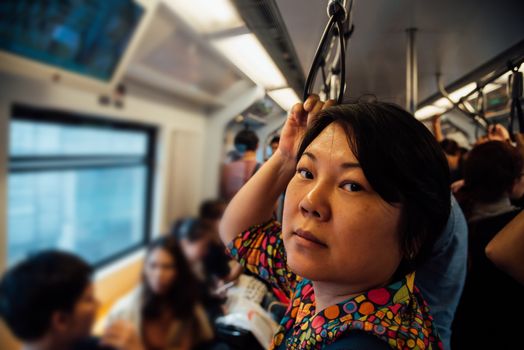 Asian woman travel on skytrain train in city. Many people in city used skytrain to save time.