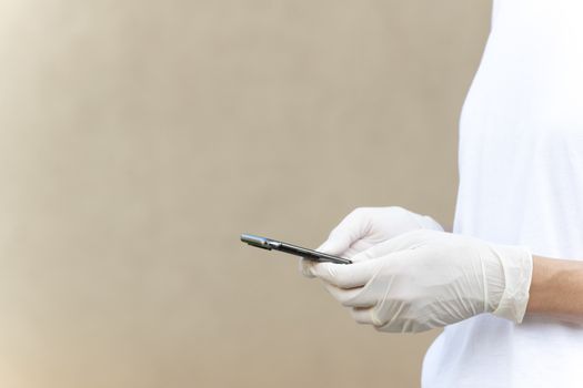 Woman wearing protective gloves and texting or chatting with her Smartphone. Close-up on hands, natural lighting and copy space her side