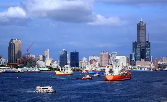 KAOHSIUNG, TAIWAN -- AUGUST 13 , 2017: A busy scene with freight ships and tugboats in Kaohsiung port. In the back one can see the skyline of the city.

