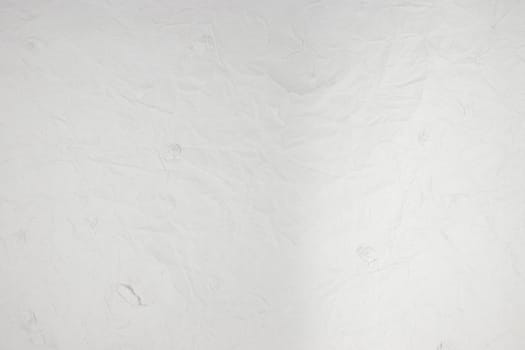 Handmade recycled paper background texture with rough patches.