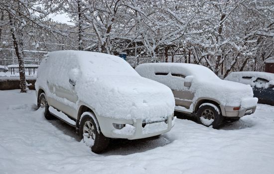 Snow covered cars in a city street.