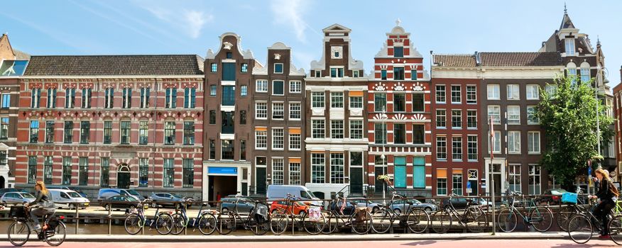 AMSTERDAM, NETHERLANDS - MAY 30: View of Amsterdam city and typical dutch houses on May 30, 2014 in Amsterdam, Netherlands.

Amsterdam, Netherlands - May 30, 2014: View of Amsterdam city and typical dutch houses. People ride bicycles.