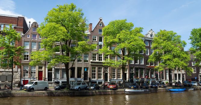 AMSTERDAM, NETHERLANDS - MAY 30: Amsterdam canals on May 30, 2014 in Amsterdam, Netherlands. View of Amsterdam canals and typical dutch houses.

Amsterdam, Netherlands - May 30, 2014: View of Amsterdam canals and typical dutch houses. People are walking by street.