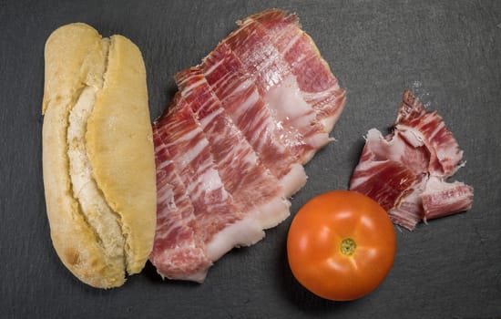 Iberian acorn ham sandwich with its knife, tomato and garlic. Spanish typical tapas