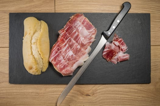 Iberian acorn ham sandwich with its knife, tomato and garlic. Spanish typical tapas