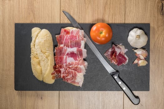 Iberian acorn ham sandwich with its knife, tomato and garlic. Spanish typical tapas