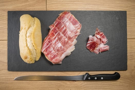 Iberian acorn ham sandwich with its knife, tomato and garlic. Spanish typical tapas