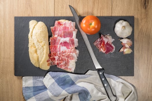 Iberian acorn ham sandwich with its knife, tomato and garlic. Spanish typical tapas