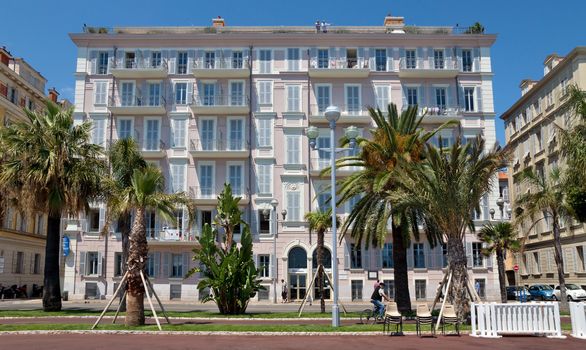 NICE, FRANCE - JUNE 3, 2014: Architecture along Promenade des Anglais. It is a symbol of the Cote d'Azur and was built in 1830 at the expense of the British colony.

Nice, France - June 3, 2014: Architecture along Promenade des Anglais. It is a symbol of the Cote d'Azur and was built in 1830 at the expense of the British colony. People are walking by street.