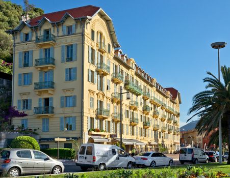 NICE, FRANCE - JUNE 5, 2014: Architecture along Promenade des Anglais. Promenade des Anglais is a symbol of the Cote d'Azur and was built in 1830 at the expense of the British colony.

Nice, France - June 5, 2014: Architecture along Promenade des Anglais. Promenade des Anglais is a symbol of the Cote d'Azur and was built in 1830 at the expense of the British colony. People are walking by street.