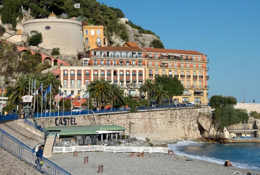 NICE, FRANCE - JUNE 5, 2014: Architecture along Promenade des Anglais. Promenade des Anglais is a symbol of the Cote d'Azur and was built in 1830 at the expense of the British colony.

Nice, France - June 5, 2014: Architecture along Promenade des Anglais. Promenade des Anglais is a symbol of the Cote d'Azur and was built in 1830 at the expense of the British colony. People are walking by Promenade and are sunbathing enjoying on the beach.
