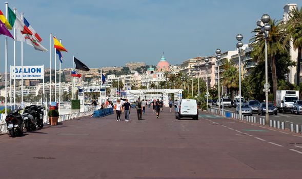 NICE, FRANCE - JUNE 6, 2014: Pedestrians walking on Promenade des Anglais. Promenade des Anglais is a symbol of the Cote d'Azur and was built in 1830 at the expense of the British colony.

Nice, France - June 6, 2014: Pedestrians walking on Promenade des Anglais. Promenade des Anglais is a symbol of the Cote d'Azur and was built in 1830 at the expense of the British colony. People are resting and are walking.