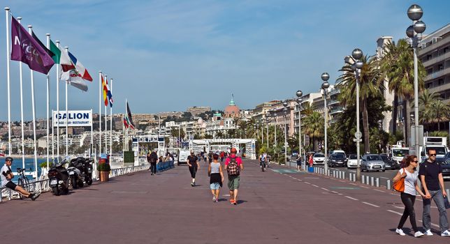 NICE, FRANCE - JUNE 6, 2014: Pedestrians walking on Promenade des Anglais. Promenade des Anglais is a symbol of the Cote d'Azur and was built in 1830 at the expense of the British colony.

Nice, France - June 6, 2014: Pedestrians walking on Promenade des Anglais. Promenade des Anglais is a symbol of the Cote d'Azur and was built in 1830 at the expense of the British colony. People are resting and are walking.