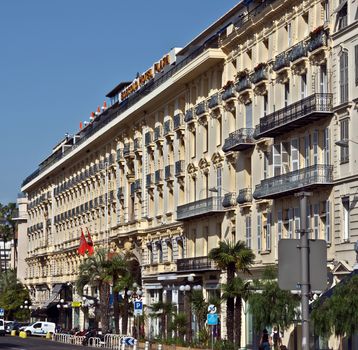 NICE, FRANCE - JUNE 8, 2014: Architecture along Promenade des Anglais. Promenade des Anglais is a symbol of the Cote d'Azur and was built in 1830 at the expense of the British colony.

Nice, France - June 8, 2014: Architecture along Promenade des Anglais. Promenade des Anglais is a symbol of the Cote d'Azur and was built in 1830 at the expense of the British colony. People are walking by street.