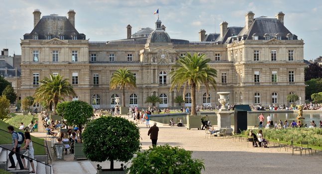 PARIS, FRANCE - JUNE 8, 2014: The Luxembourg Palace in The Jardin du Luxembourg. View on the main facade and water pond.

Paris, France - June 8, 2014: The Luxembourg Palace in The Jardin du Luxembourg. View on the main facade and water pond. Many people are resting there.
