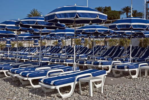 City Beach with blue umbrella near Promenade des Anglais in city of Nice, France.