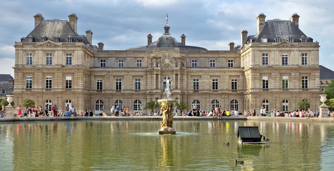 PARIS, FRANCE - JUNE 8, 2014: The Luxembourg Palace in The Jardin du Luxembourg. View on the main facade and water pond.

Paris, France - June 8, 2014: The Luxembourg Palace in The Jardin du Luxembourg. View on the main facade and water pond. Many people are resting there.