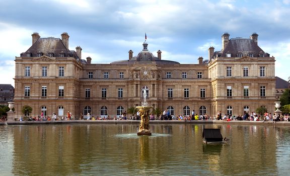 PARIS, FRANCE - JUNE 8: The Luxembourg Palace in The Jardin du Luxembourg on June 8, 2014 in Paris, France. View on the main facade and water pond. Many people are resting there.

Paris, France - June 8, 2014: The Luxembourg Palace in The Jardin du Luxembourg. View on the main facade and water pond. Many people are resting there.