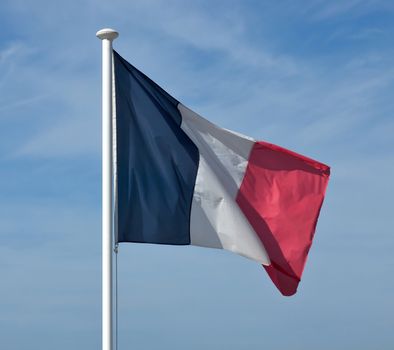 Flag of France waving against blue sky.
