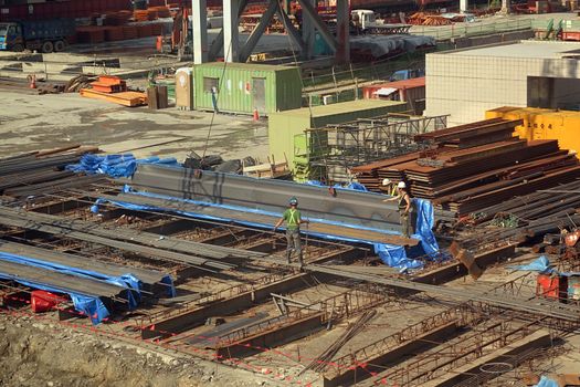 KAOHSIUNG, TAIWAN -- MAY 31, 2014: Workers move steel girders at a large construction site at the main Kaohsiung railway station.