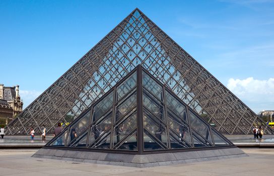 PARIS, FRANCE - JUNE 9: Pyramid near Louvre Museum on June 9, 2014 in Paris, France. Louvre is one of the biggest Museum in the world, receiving more than 8 million visitors each year. 

Paris, France - June 9, 2014: Pyramid near Louvre Museum. Louvre is one of the biggest Museum in the world, receiving more than 8 million visitors each year. People are walking near pyramid.