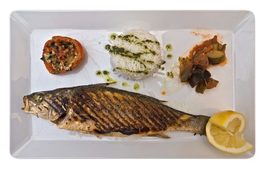 Roasted fish with rice, lemon and vegetables on the dish isolated on white. Clipping path included.