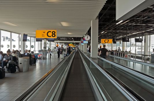 AMSTERDAM, NETHERLANDS - JUNE 12, 2014: Escalator for the movement of passengers between terminals. Schiphol is Europe's fifth busiest airport, it was open on Sept 16, 1916.

Amsterdam, Netherlands - June 12, 2014: Escalator for the movement of passengers between terminals. Schiphol is Europe's fifth busiest airport, it was open on Sept 16, 1916. People are moving by airport.
