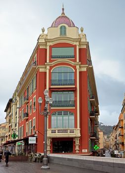 NICE, FRANCE - APRIL 27: The architecture of buildings on the Place Massena on April 27, 2013 in Nice, France. The square is bordered by red ochre buildings of Italian architecture.

Nice, France - April 27, 2013: The architecture of buildings on the Place Massena. The square was reconstructed in 1979. The square is bordered by red ochre buildings of Italian architecture. People are walking.