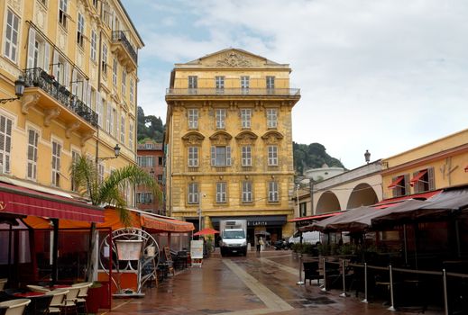 NICE, FRANCE - APRIL 27: Old building and a cafe in the Cours Saleya on April 27, 2013 in Nice, France. The Cours Saleya is a place of outdoor restaurants and a market. 

Nice, France - April 27, 2013: Old building and a cafe in the Cours Saleya. 
The Cours Saleya is a place of outdoor restaurants, boutiques and a market. 