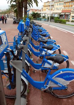 NICE, FRANCE - APRIL 27: Public Bicycles Sharing Station on April 27, 2013 in Nice, France. One of 120 stations in Nice. This service offers over 1200 self-service bicycles.

Nice, France - April 27, 2013: Row of public bikes for rent along the street. People are walking. Nice has 120 stations. This service offers over 1200 self-service bicycles.