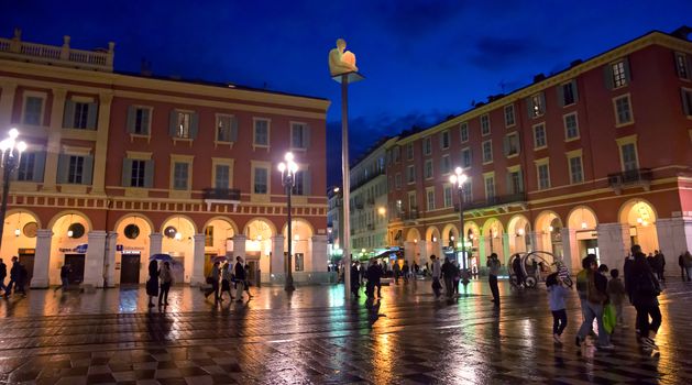 NICE, FRANCE - APRIL 28: The Place Massena at night on April 28, 2013 in Nice, France. The square was reconstructed in 1979. 

Nice, France - April 28, 2013: The Place Massena at night. People are walking. The square was reconstructed in 1979. People are walking by square.