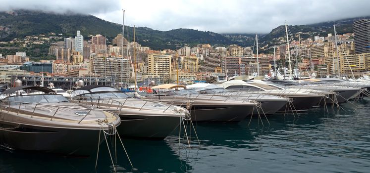 MONTE CARLO, MONACO - APRIL 28: Fashionable yachts in the port Hercules and view on the city on April 28, 2013 in Monte Carlo, Monaco. 

Monte Carlo, Monaco - April 28, 2013: Fashionable yachts in the port Hercules and view on the city.