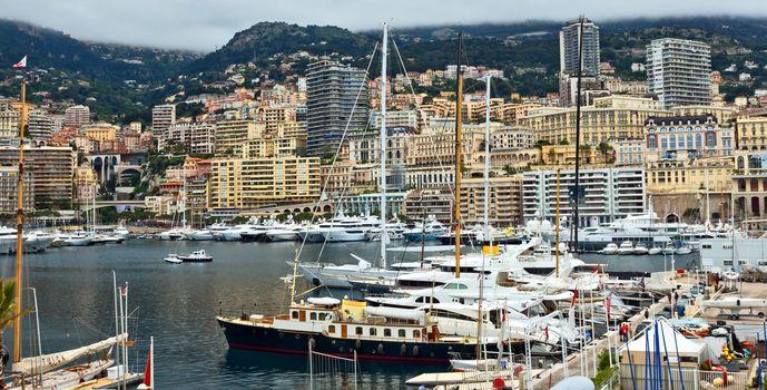 MONTE CARLO, MONACO - APRIL 28: Fashionable yachts in the port Hercules and view on the city on April 28, 2013 in Monte Carlo, Monaco. 

Monte Carlo, Monaco - April 28, 2013: Fashionable yachts in the port Hercules and view on the city.