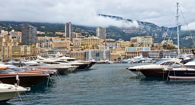 MONTE CARLO, MONACO - APRIL 28: Fashionable yachts in the port Hercules and view on the city on April 28, 2013 in Monte Carlo, Monaco. 

Monte Carlo, Monaco - April 28, 2013: Fashionable yachts in the port Hercules and view on the city.