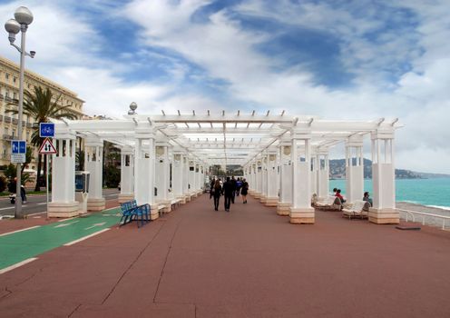 NICE, FRANCE - APRIL 27: Pedestrians walking on Promenade des Anglais on April 27, 2013 in Nice, France. It is a symbol of the Cote d'Azur and was built in 1830 at the expense of the British colony.

Nice, France - April 27, 2013 : Pedestrians walking on Promenade des Anglais. Promenade des Anglais is a symbol of the Cote d'Azur and was built in 1830 at the expense of the British colony.