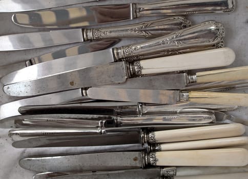 Background of heap old fashioned silver knives.