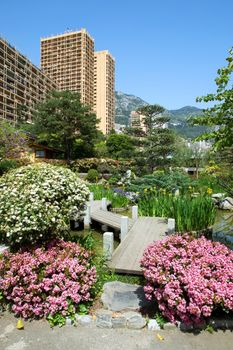Japanese garden of Monaco, with a pond and Monte Carlo buildings behind.