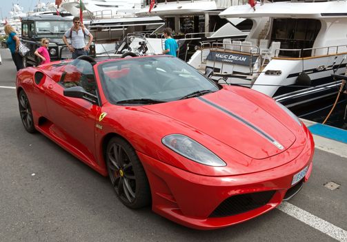 MONTE CARLO, MONACO - MAY 1: Luxury sportscar and luxurious yachts in Port Hercules on May 1, 2013 in Monte Carlo, Monaco.

Monte Carlo, Monaco - May 1, 2013: Luxury sportscar and luxurious yachts in Port Hercules. People look at car.