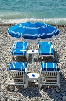 Beach with blue umbrellas near Promenade des Anglais in city of Nice, France.